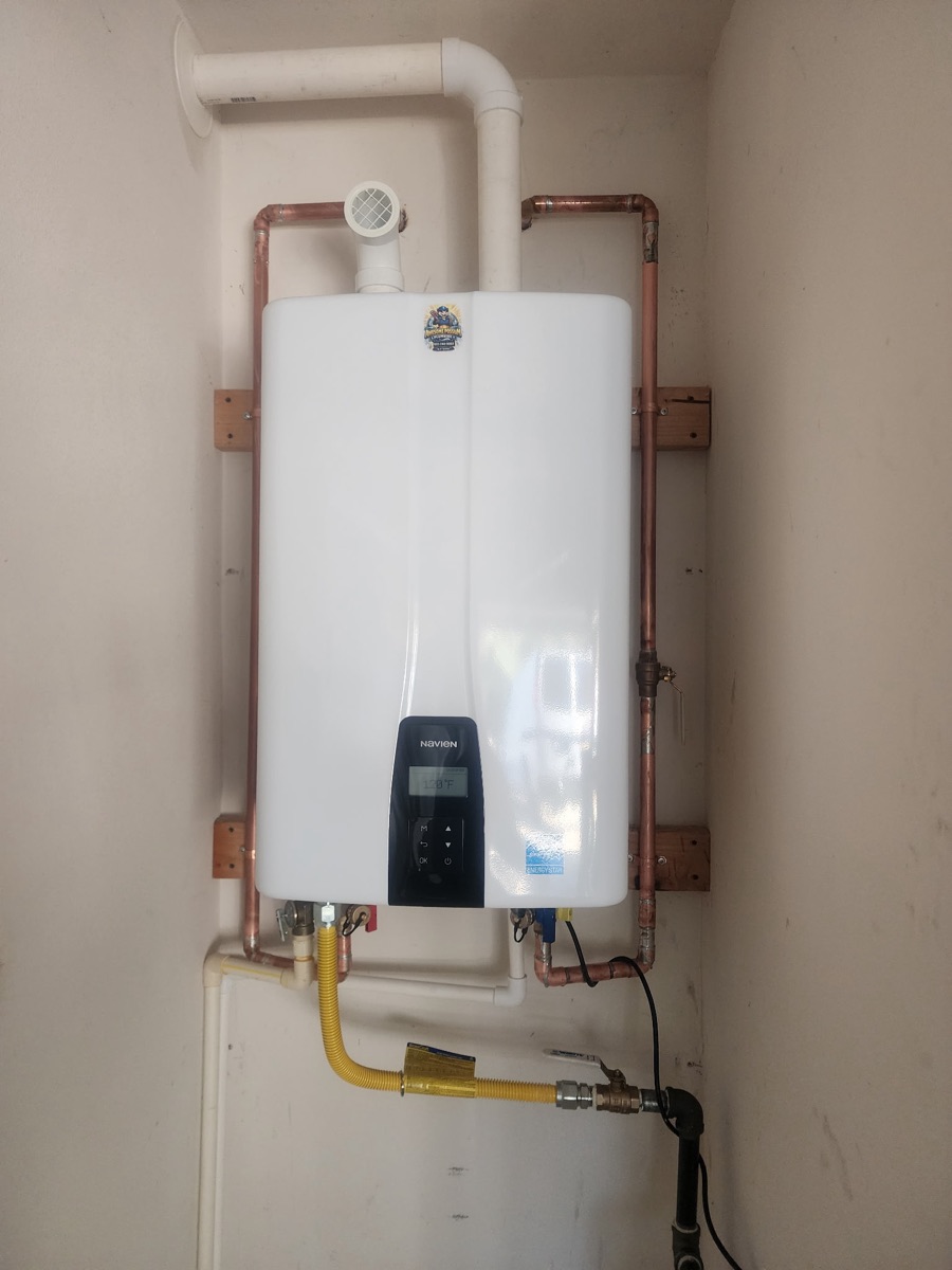 Navien tankless water heater installed on a garage wall by Awesome Possum Plumbing, with new copper water lines and a yellow gas line